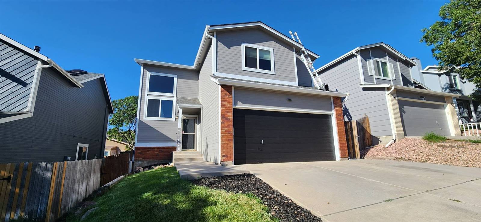 Finished exterior repaint, gray siding with brick accents